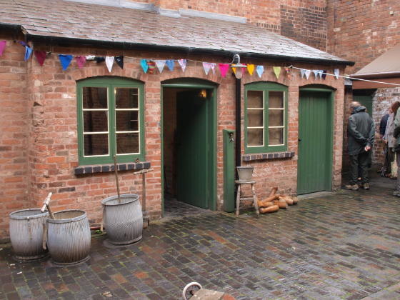 A one-storey brick building in a brick courtyard